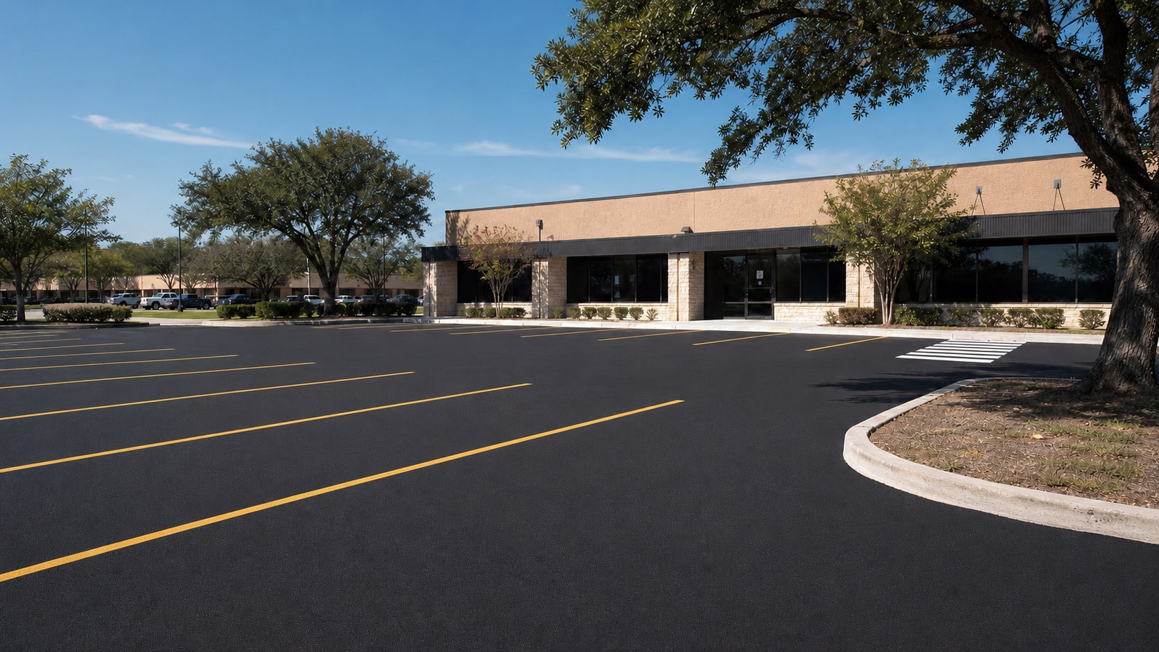Freshly sealcoated commercial parking lot with clear yellow striping and a modest storefront
